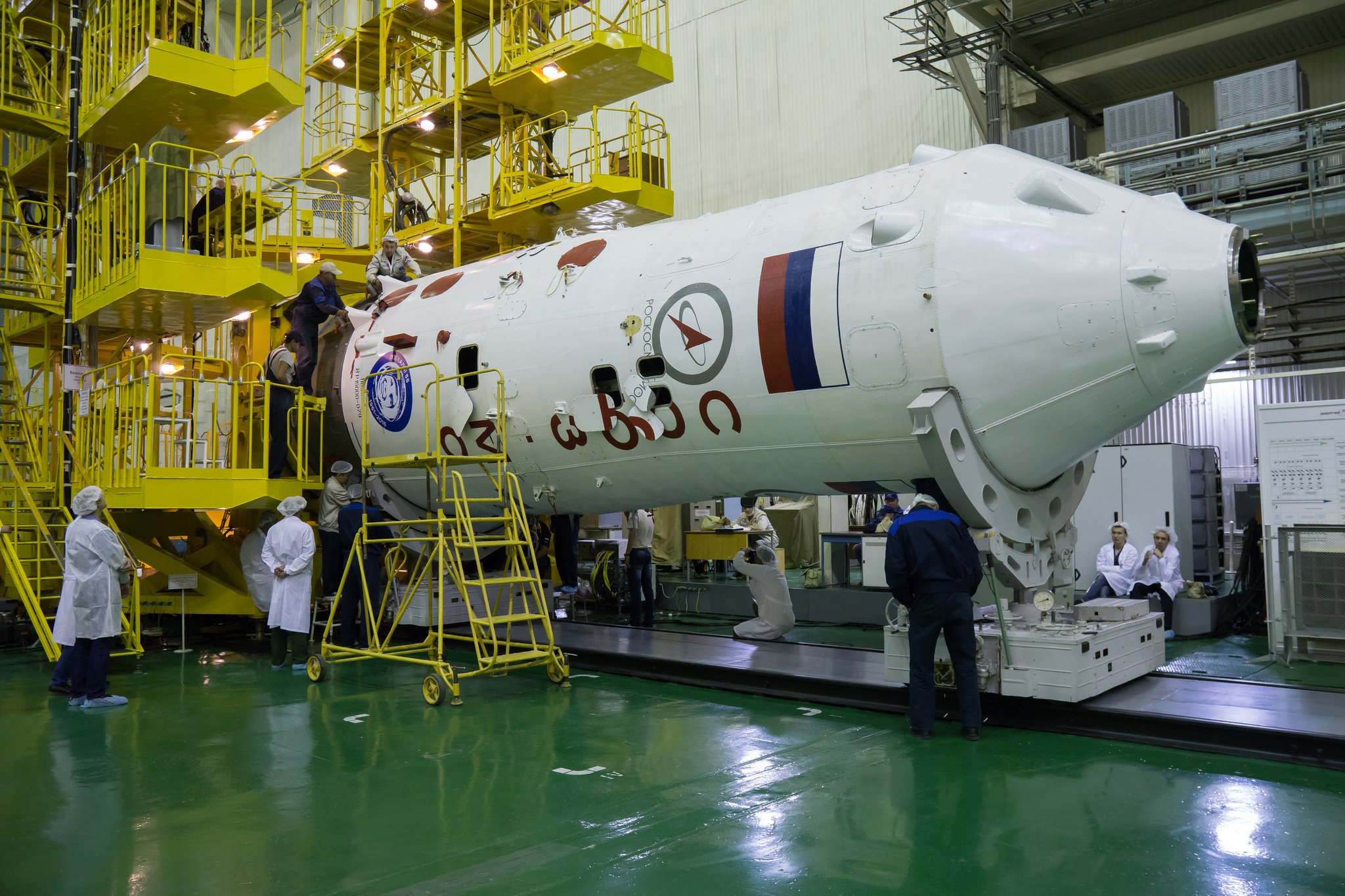 A large outer casing for the top of a rocket is inspected while suspended horizontally.