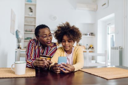 October Prime Day: An African American teenage girl enjoying at home with grandmother and shopping online.