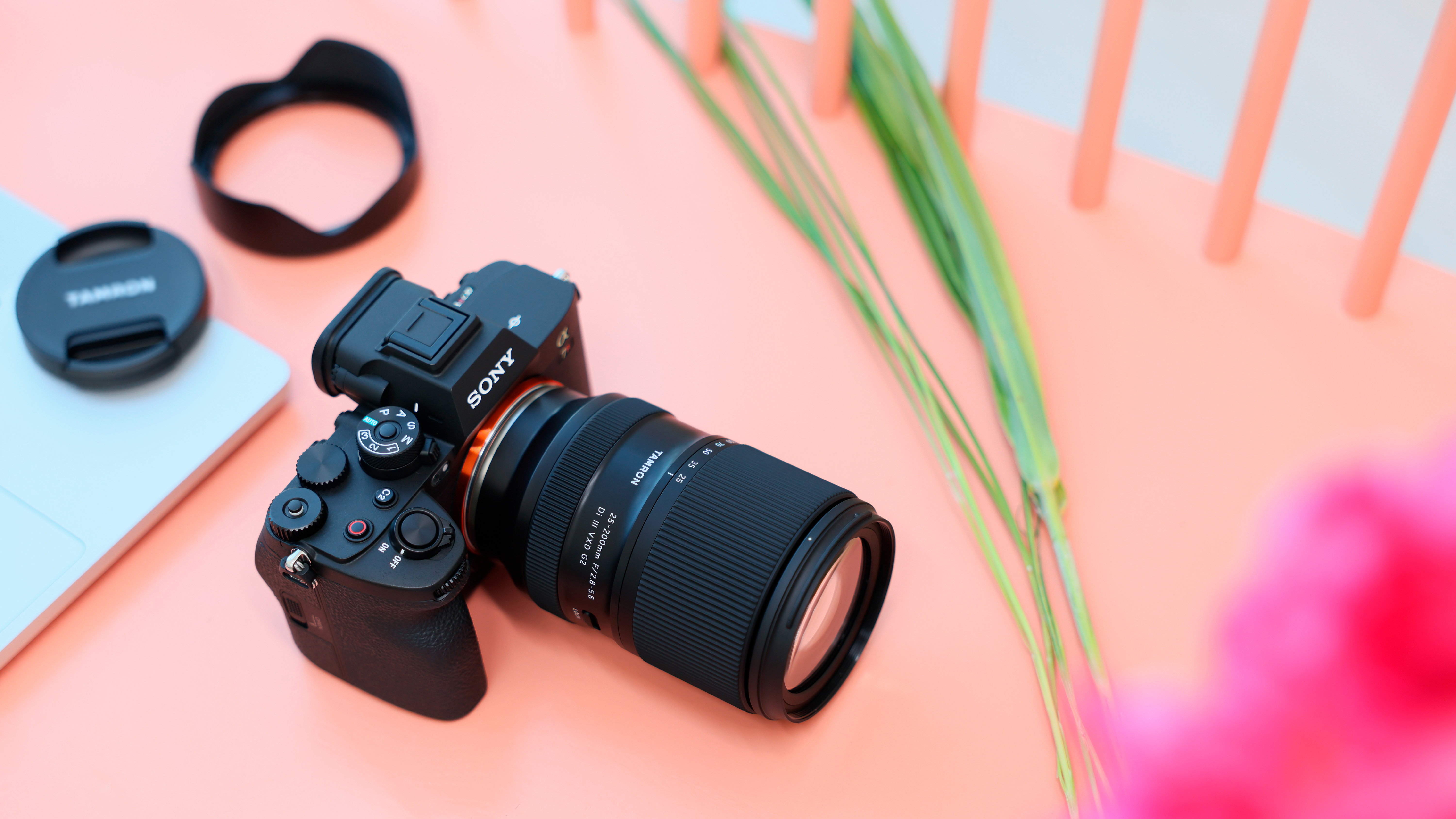 The Tamron 25-200mm f/2.8-5.6 DI III VXD G2 mounted on a Sony camera sitting on a coral-colored chair