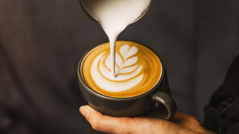 A person doing latte art in a black coffee mug 