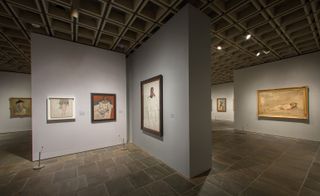 grey walls with various artworks in frames on display at Met Breuer