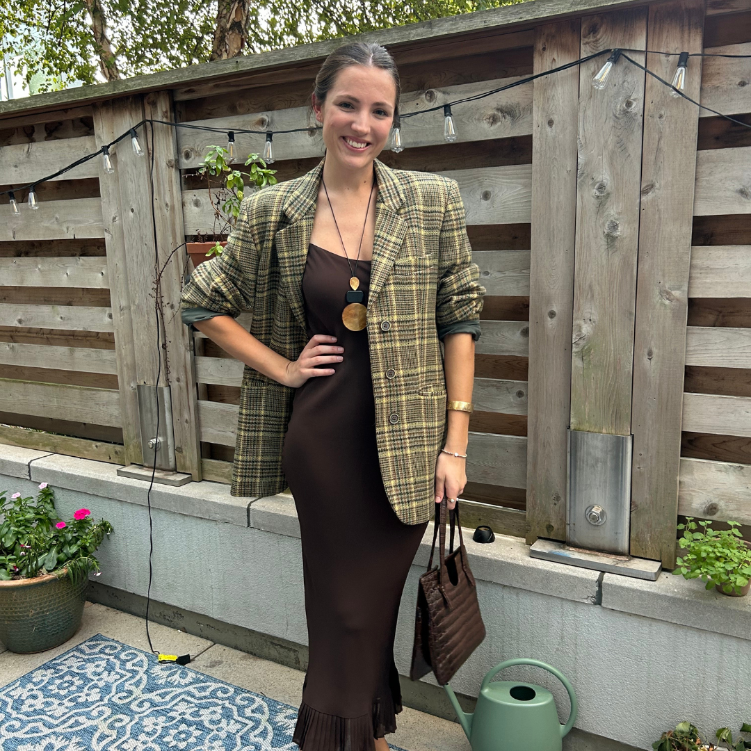a woman standing in a green blazer and a brown dress