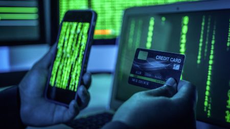 A hand holding a credit card and phone displaying digital code