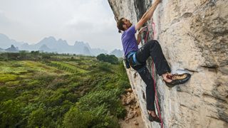 A man rock climbing with trees in the background