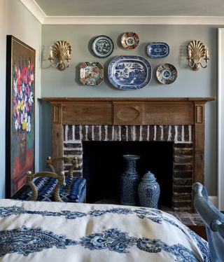 A bedroom with blue patterned sheets and blue pottery