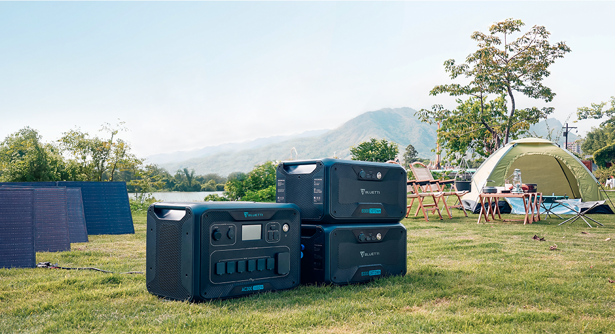 Bluetti AC300 generator and 2 B300 batteries with solar panels at a campsite.