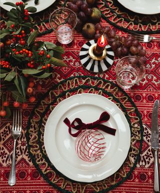 Christmas table with a red block-print tablecloth from Sarah K, raffia placemats, berries and glass baubles