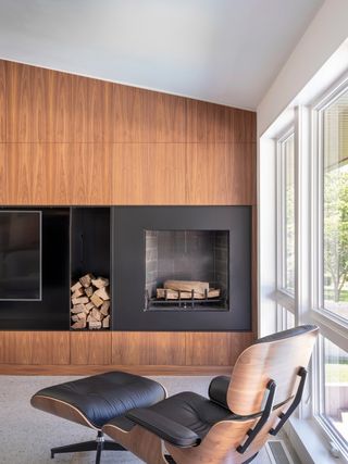 modern timber-clad fireplace wall with integrated fireplace, polished concrete floor, eames lounge chair