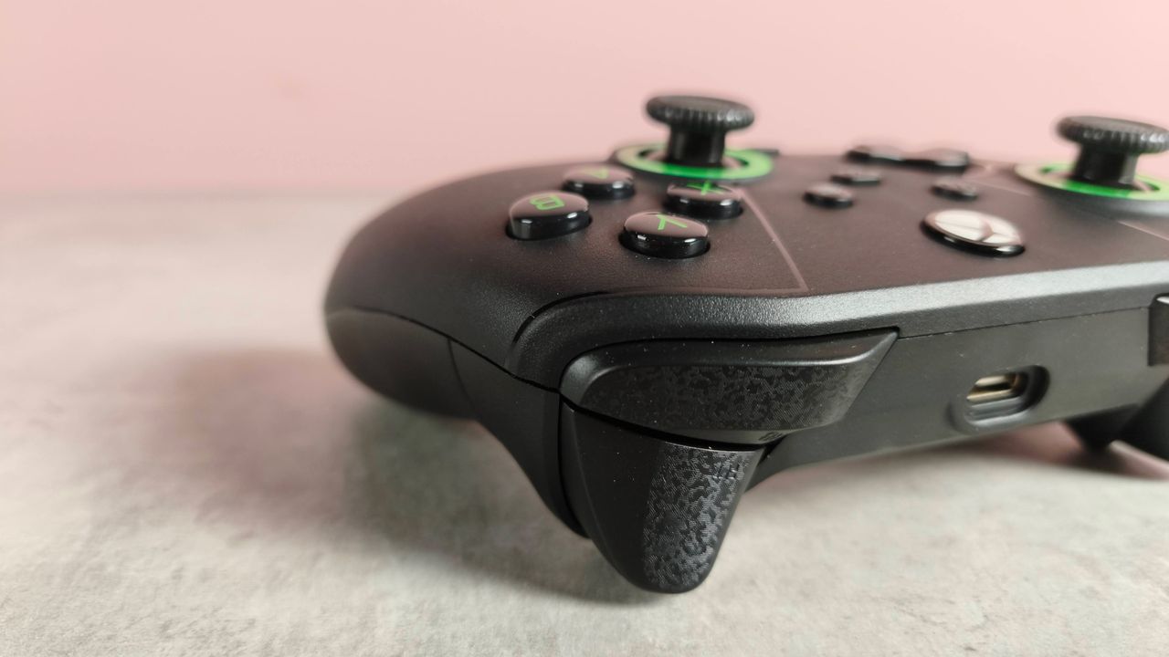Close-up of right shoulder buttons on Drakong Challenger, on a desk with pink wall in background