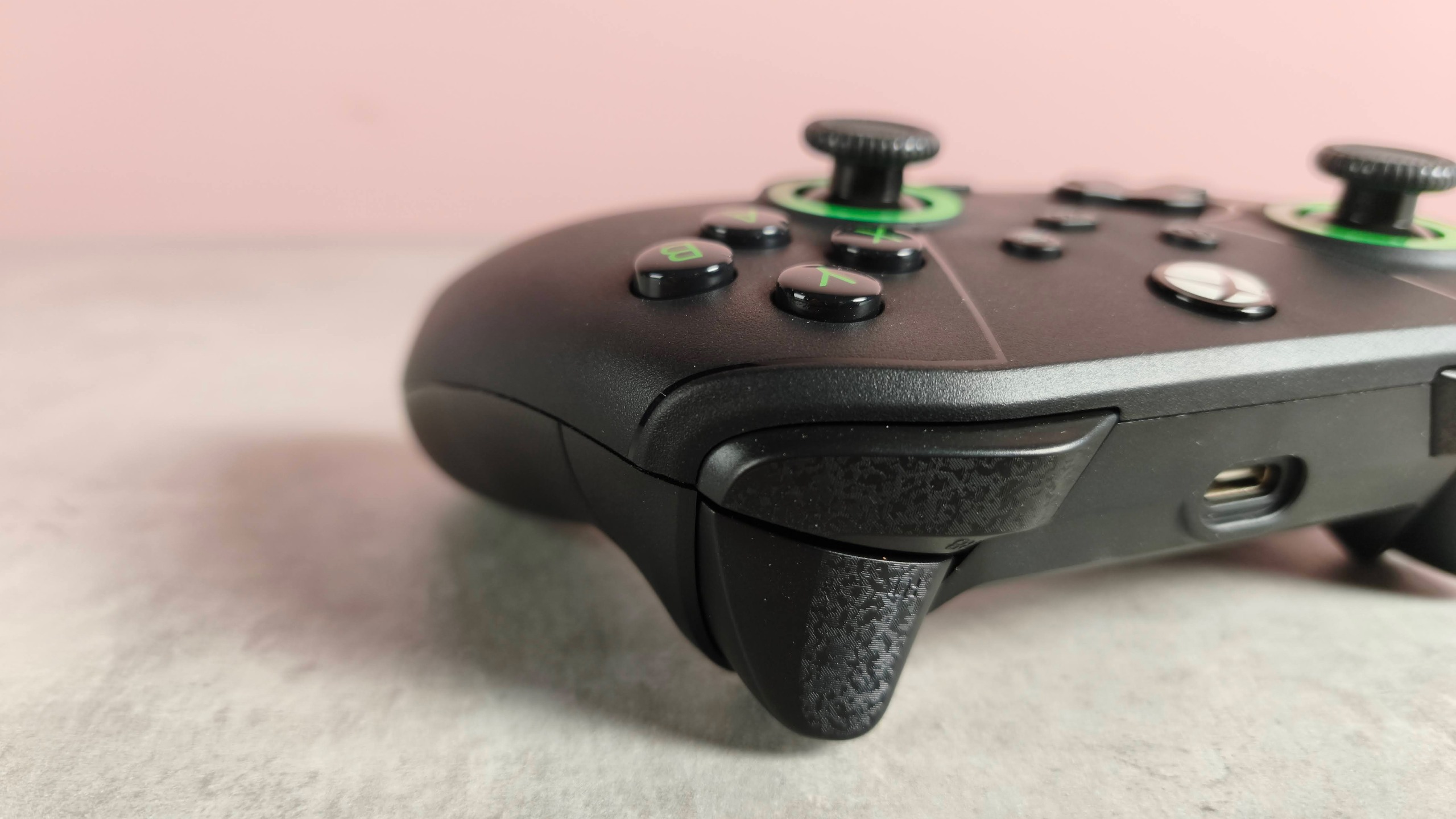 Close-up of right shoulder buttons on Drakong Challenger, on a desk with pink wall in background