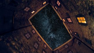 Starry night sky seen through the courtyard of an illuminated building