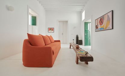 Minimalist living room with orange sofa, wooden table and a green door