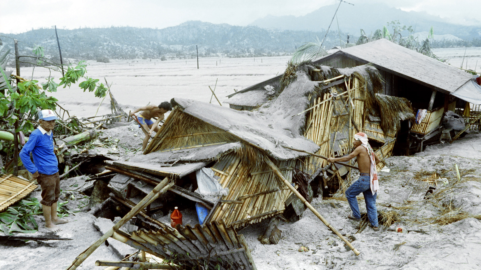 Villagers try to rebuild a hut that is covered in ash.