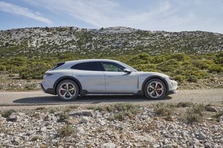 Porsche Taycan Gran Turismo under a blue sky with greenery and rocks surrounding