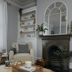 Upholstered beige chair next to fireplace with white framed mirror on top