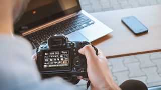 Man looking at camera settings in front of a laptop