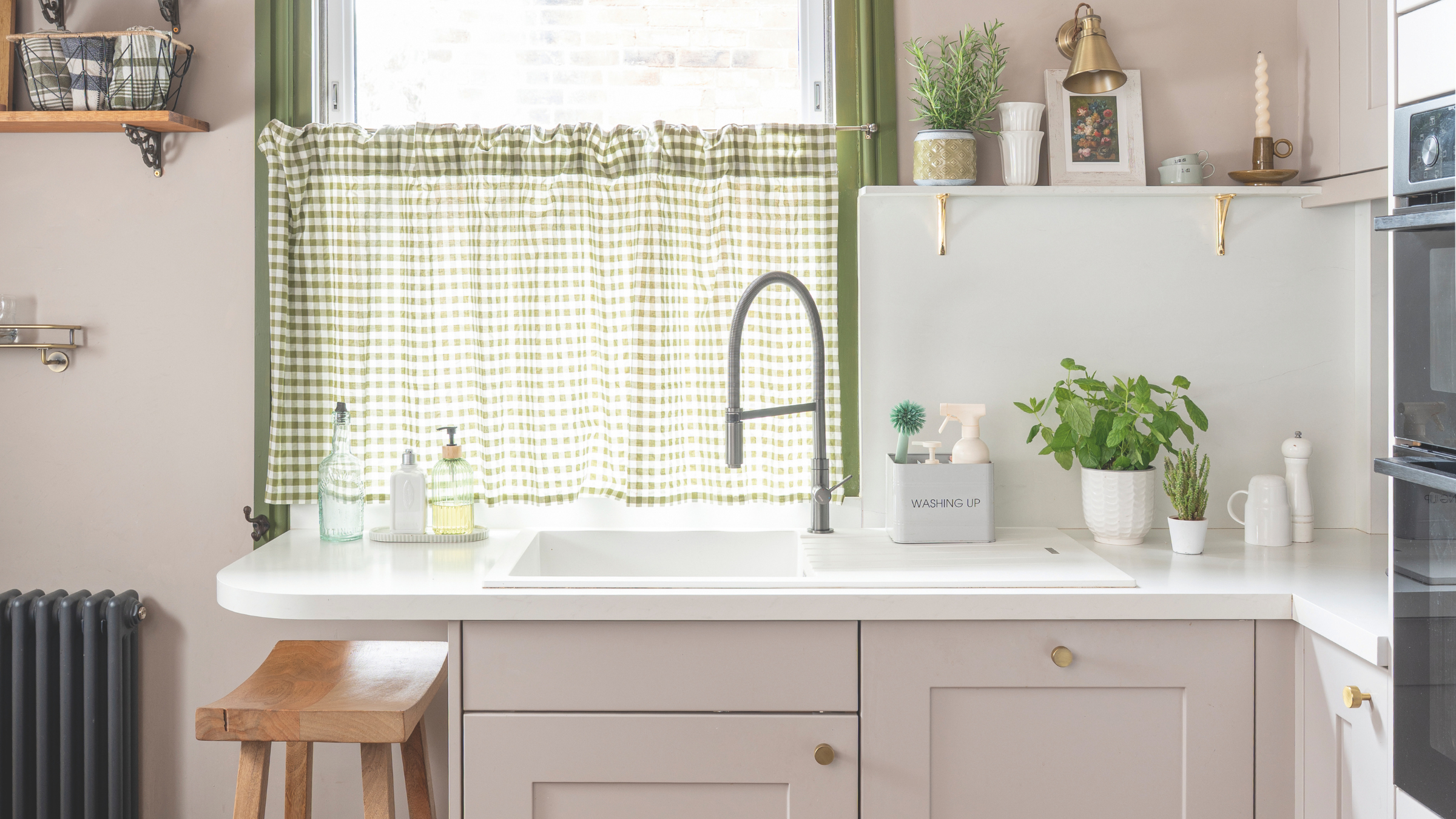 Small kitchen, with pink cupboards and ginham window cover.