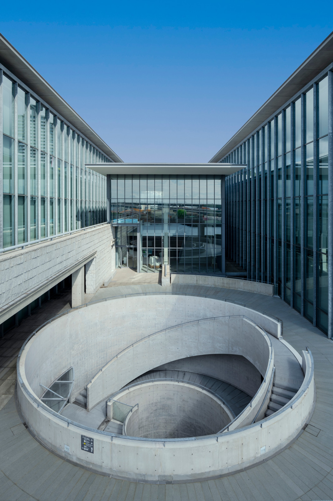 A modernist museum cast from cement, glass, and iron features a spiraling staircase at its center.