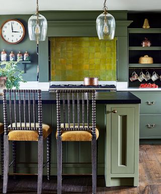 Green kitchen with island, lime green tile splashback, barstools and glass pendants