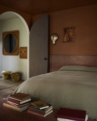 bedroom with orange walls, red ceiling and light sage bedding