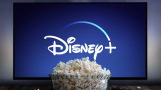 En stor bolle med popcorn foran en TV-skjerm med Disney+-logoen på skjermen