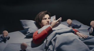 Mark lying in bed surrounded by faceless babies