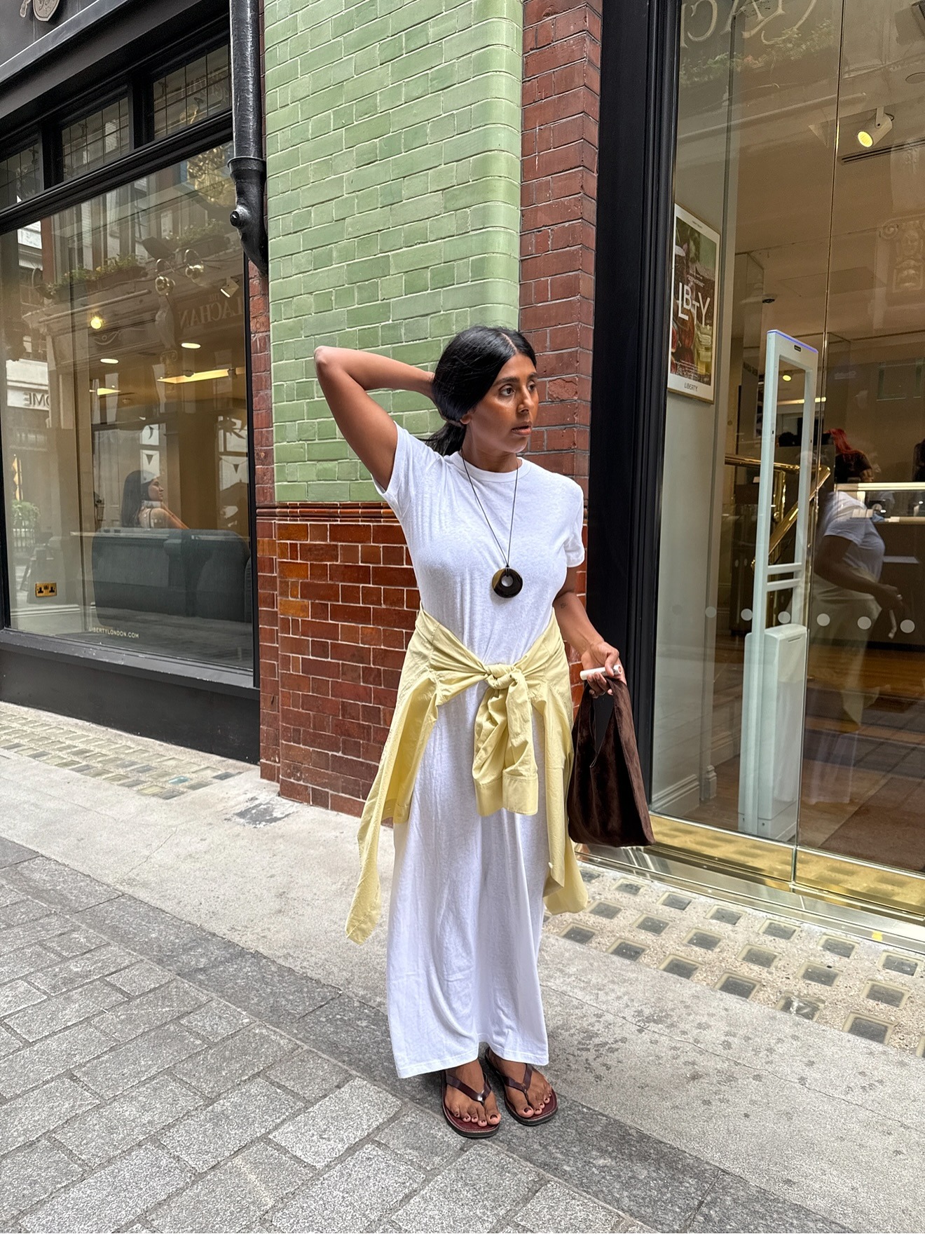 Woman in white dress with yellow sweater around waist