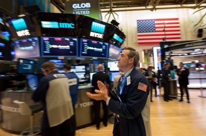 A trader claps after the Dow closes above 23,000 on Oct. 18, 2017.