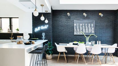 monochrome kitchen with black exposed brick wall and dining table