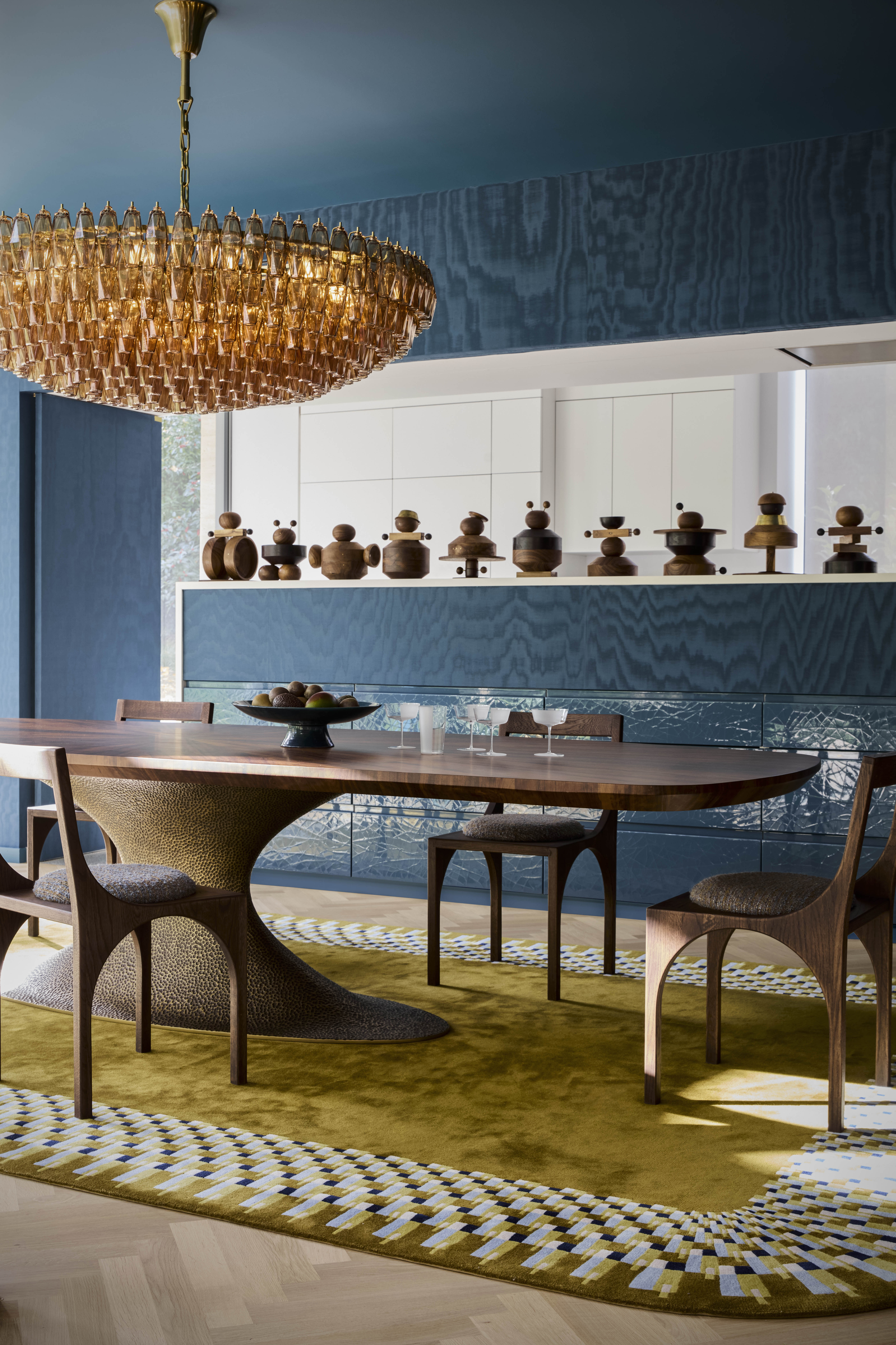 a room with all blue walls and ceilings, with a chartreuse rug and bold chandelier