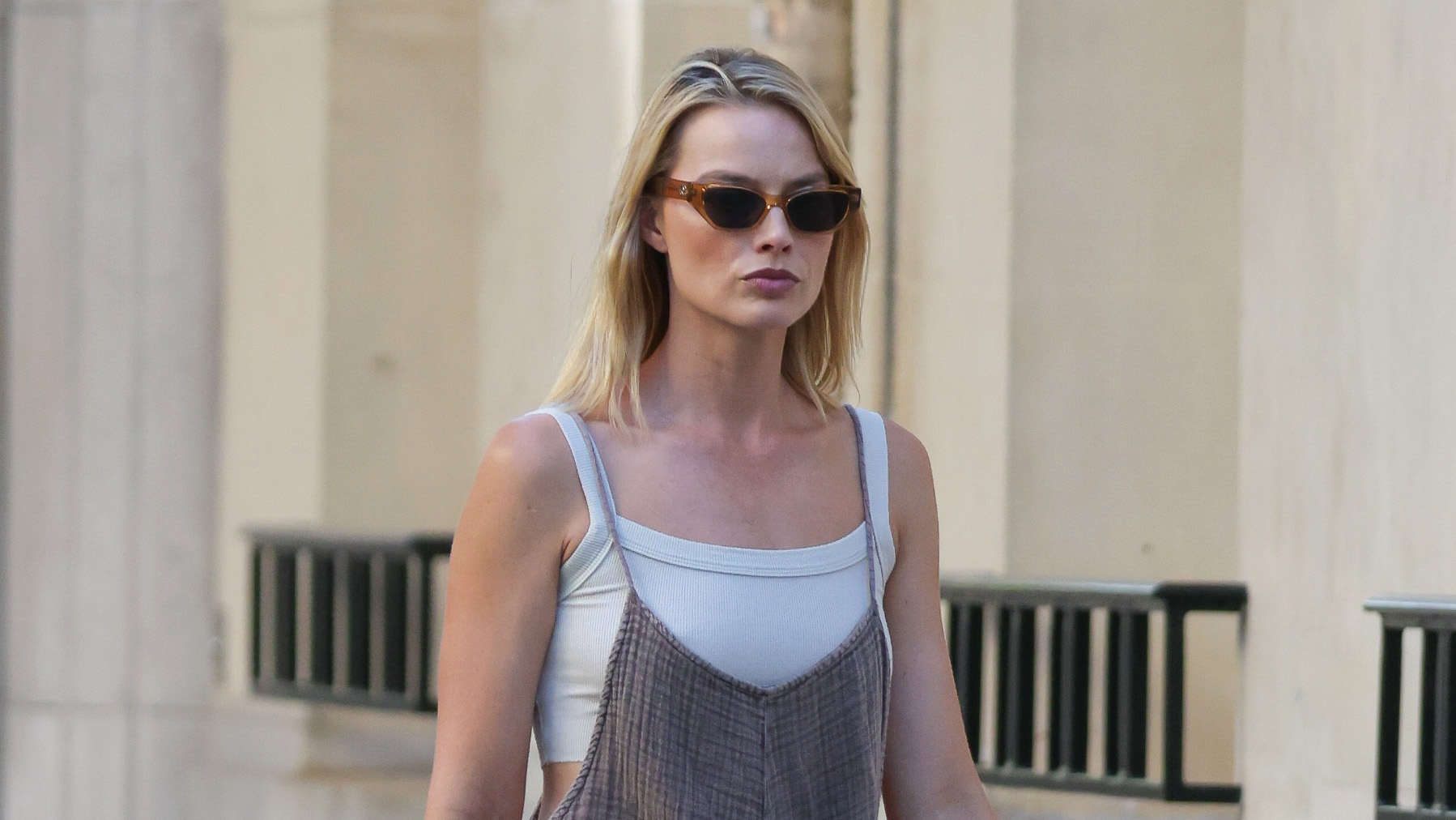 Margot Robbie wearing a casual knit jumpsuit over a white sports bra with suede Tory Burch slides in Paris