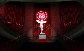 Staircase with backdrop of vinyl red curtains, neon pink sign and classical statue statement