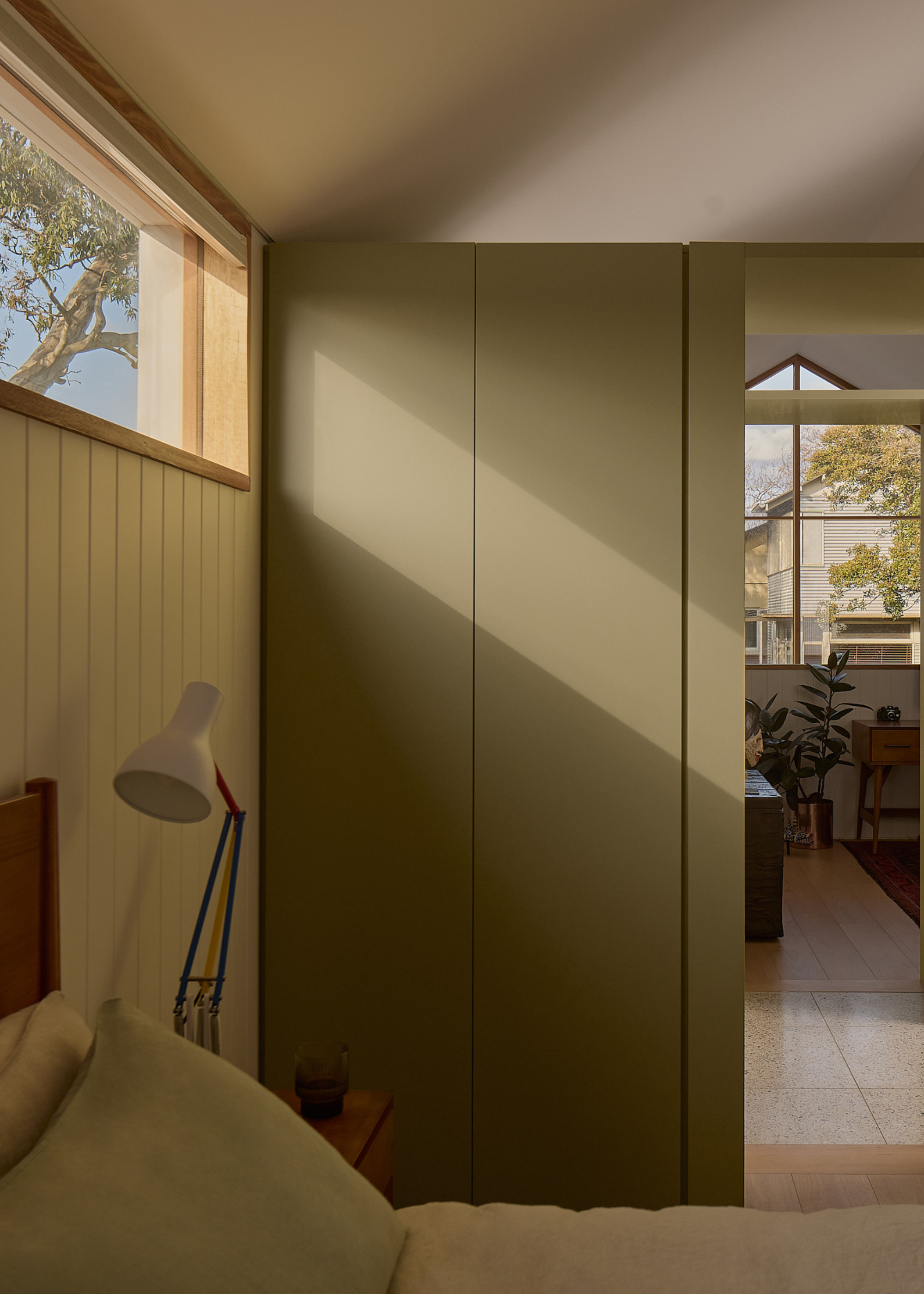 An olive green wardrobe in a small bedroom