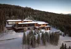Located in the Spanish Peaks of Montana, the house comprises a series of horizontal volumes, with a cantilevered section reaching into the surrounding pine forest
