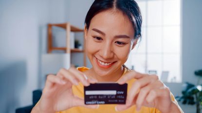 A young woman smiles as she looks at a new credit card