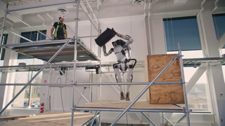 Image of Atlas the humanoid robot by Boston Dynamics throwing a bag to a worker