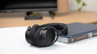Sennheiser RS 275 TV Headphones in black next to a book on a coffee table