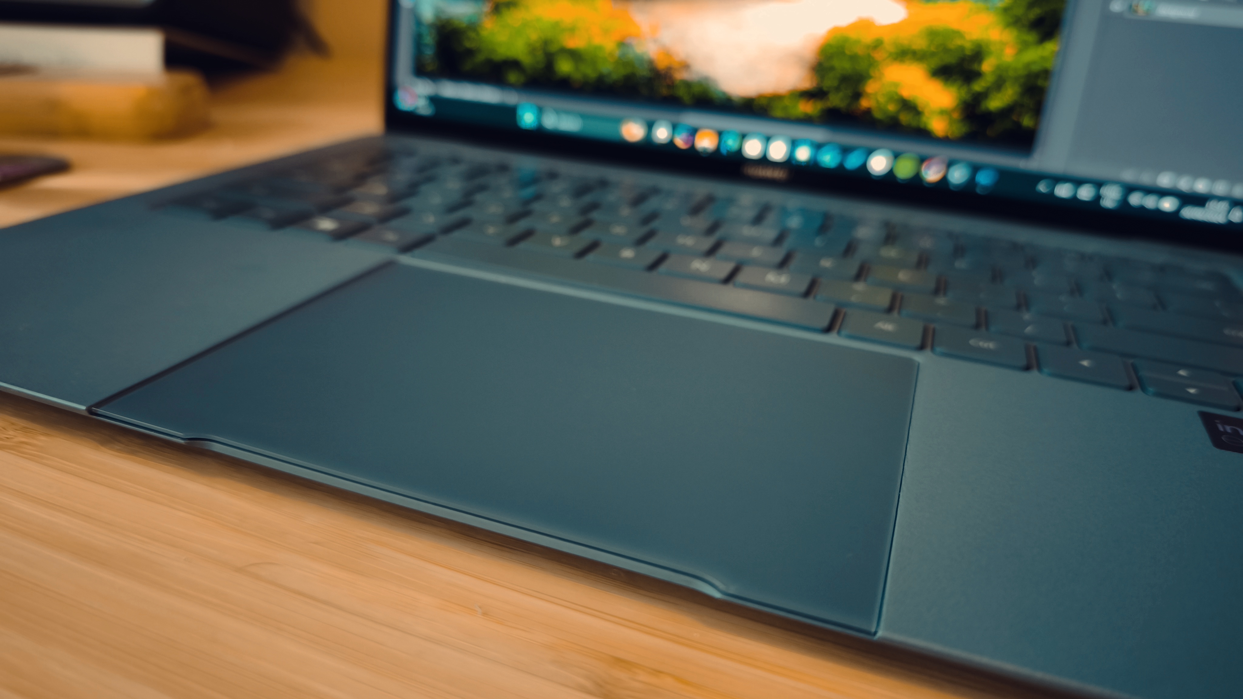 A blue Huawei Matebook X Pro laptop on a wooden desk, in front of blue and orange LED lights.