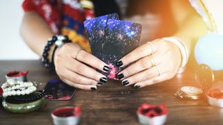 Midsection Of Woman Holding Tarot Cards At Table - stock photo