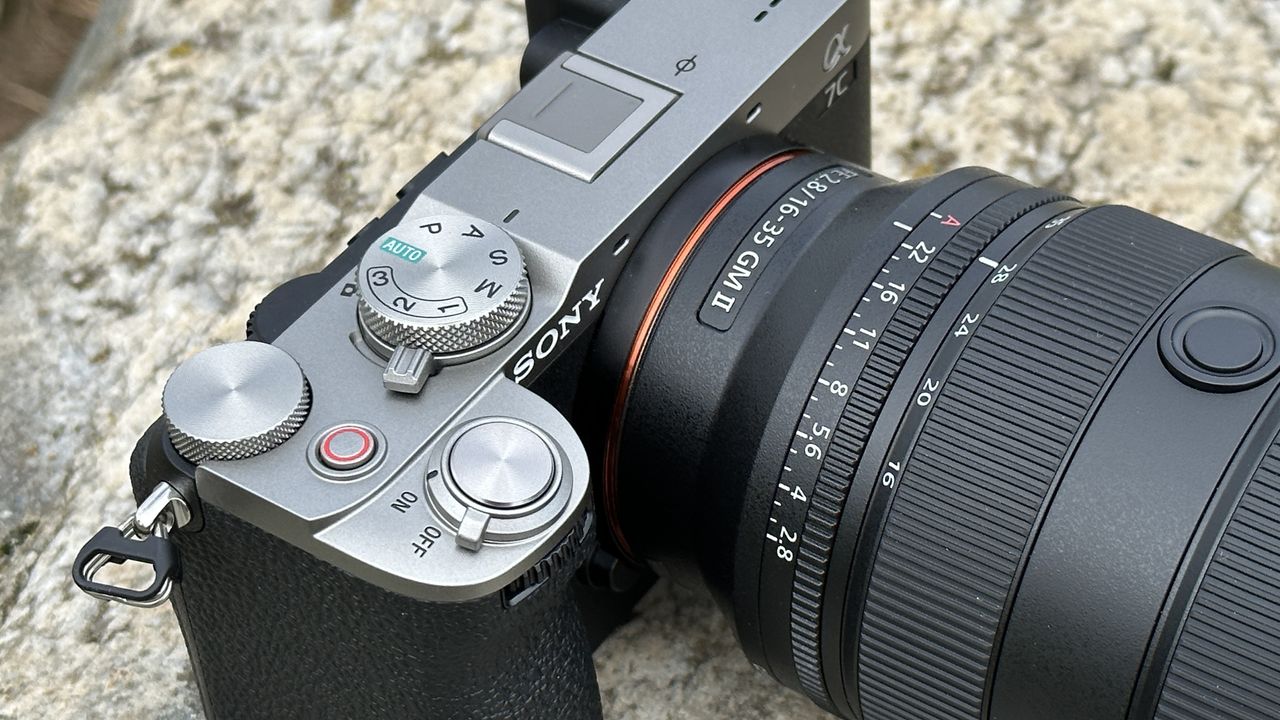 Close up of Sony A7C II mirrorless camera's top plate, outside on a rock with Sony FE 16-35mm F2.8 GM II lens attached