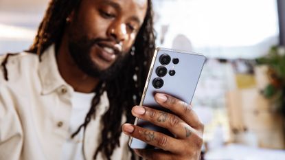 A man looking at the screen of a Samsung Galaxy S25 Ultra.