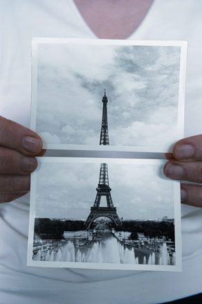 Person holding two photos of the Eiffel tower