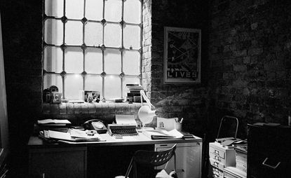 Black and white image of an office featuring a typewriter and telephone, and exposed brickwork