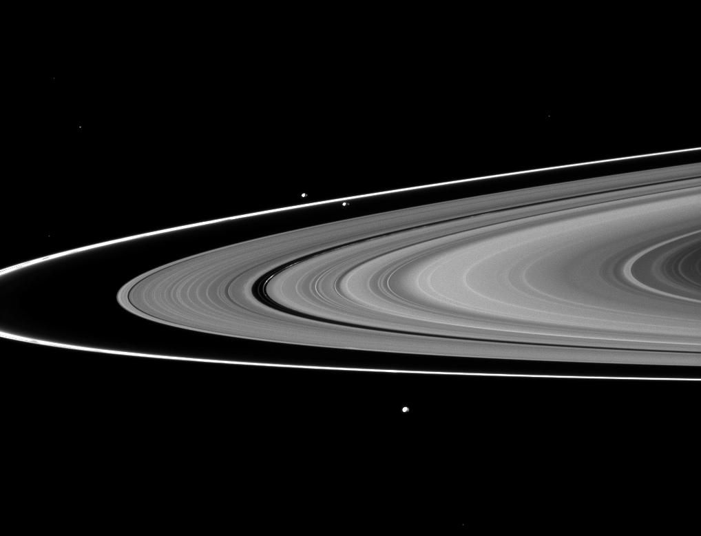 Saturn&#039;s moons Prometheus, Pandora and Epimetheus can be seen among the planet&#039;s rings in this image from the Cassini spacecraft. New views of Pan, Dasphnis, Atlas, Pandora and Epimetheus have suggested possible reasons for the strange shapes and colors of those moons.