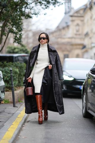 woman wearing sweater dress, coat, boots, and bag