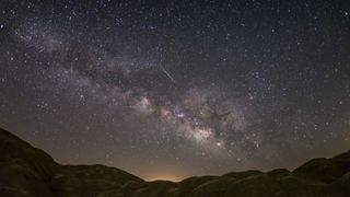 a meteor streaks through a clear night sky