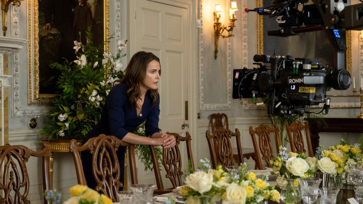 Kate Wyler (Keri Russell) leans on a dining table chair inside a stately home during filming on The Diplomat