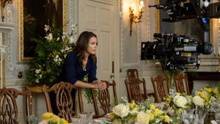 Kate Wyler (Keri Russell) leans on a dining table chair inside a stately home during filming on The Diplomat
