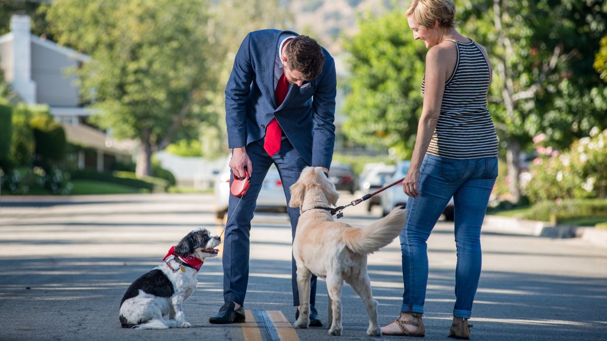 Man stopping to pet woman&#039;s dog