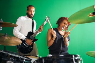 Man playing guitar and woman playing drums